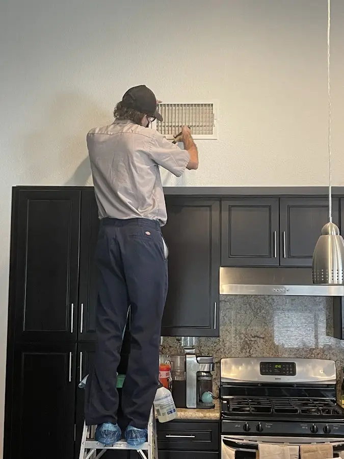 Technician inspecting an air vent during HVAC service in Los Osos
